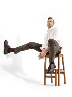 “Male fashion model dynamic sitting pose – white background commercial product photography.”contemporary menswear – high-end e-commerce fashion photography on white background.”