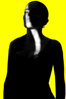 High-contrast silhouette portrait of a woman against a bright yellow background — artistic branding photo