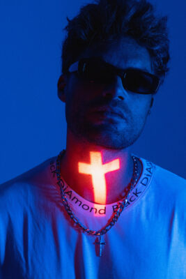 Creative personal branding portrait of a man under blue light with a glowing neon cross