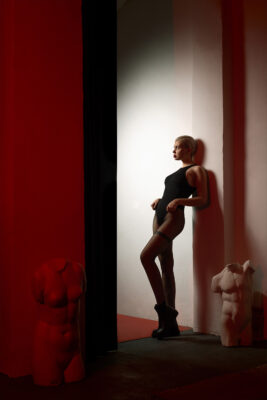 Moody personal branding portrait of a woman in red lighting with dramatic shadows