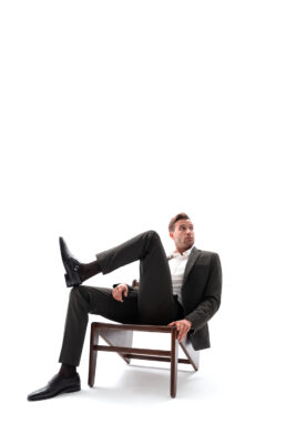 “Male model posing on chair wearing contemporary menswear – high-end e-commerce fashion photography on white background.”